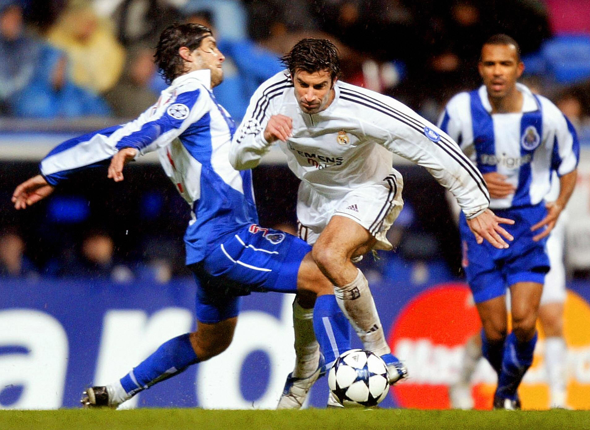 MADRID, SPAIN: Real Madrid's Portuguese Luis Figo (R) escapes a tackle of Portuguese Ricardo Costa (L) during their Champions League match Real Madrid against FC Porto in Santiago Bernabeu Stadium in Madrid 09 December 2003. AFP PHOTO/ Christophe SIMON (Photo credit should read CHRISTOPHE SIMON/AFP via Getty Images)