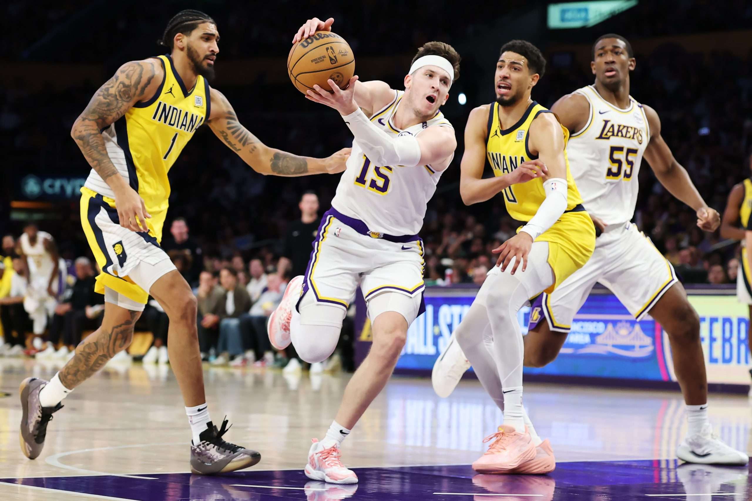 LOS ANGELES, CALIFORNIA - FEBRUARY 08: Austin Reaves #15 of the Los Angeles Lakers dribbles between Obi Toppin #1 and Tyrese Haliburton #0 of the Indiana Pacers during the third quarter at Crypto.com Arena on February 08, 2025 in Los Angeles, California(Photo by Harry How/Getty Images)