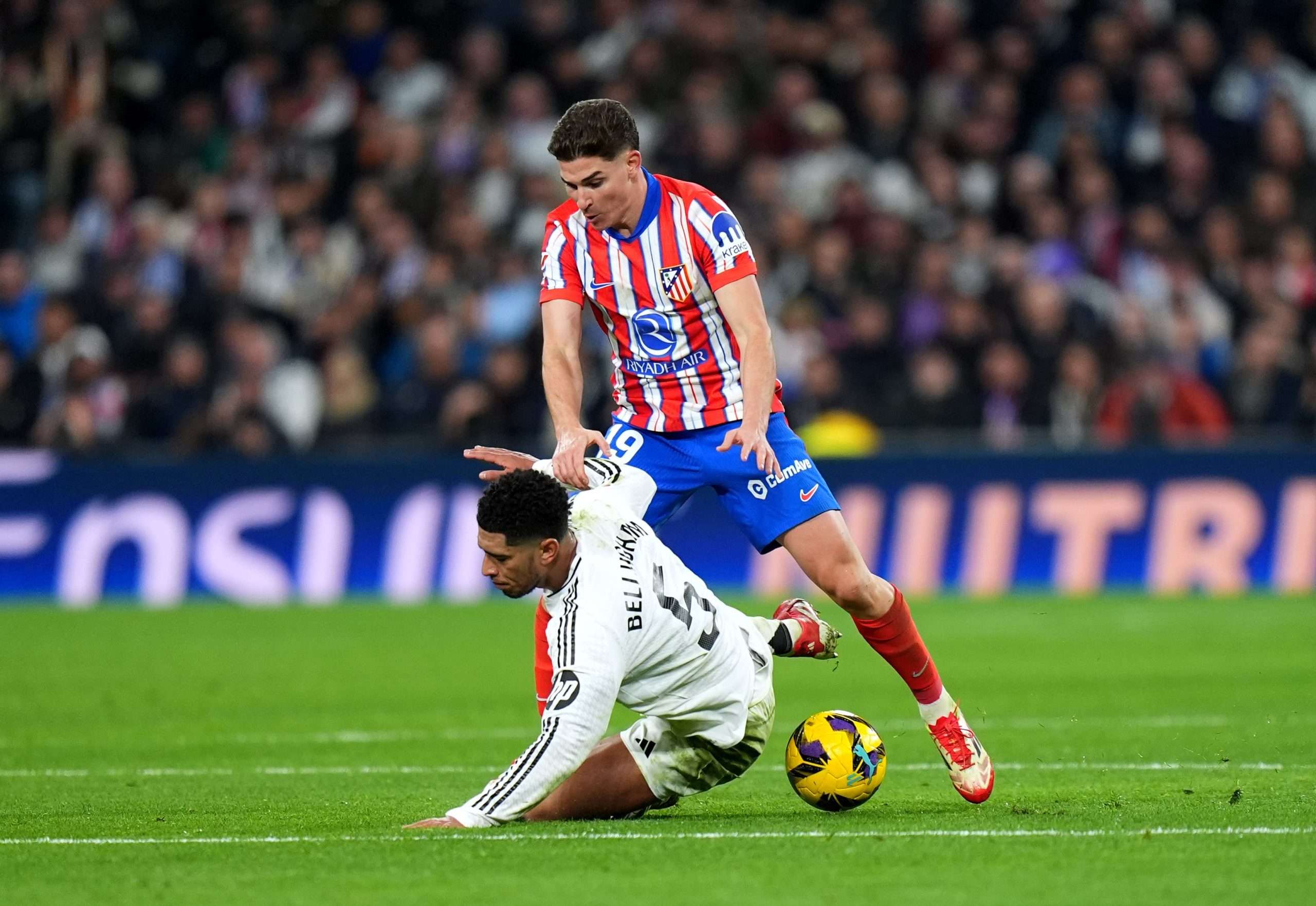 MADRID, SPAIN - FEBRUARY 08: Jude Bellingham of Real Madrid is challenged by Julian Alvarez of Atletico de Madrid during the LaLiga match between Real Madrid CF and Atletico de Madrid at Estadio Santiago Bernabeu on February 08, 2025 in Madrid, Spain. (Photo by Angel Martinez/Getty Images)